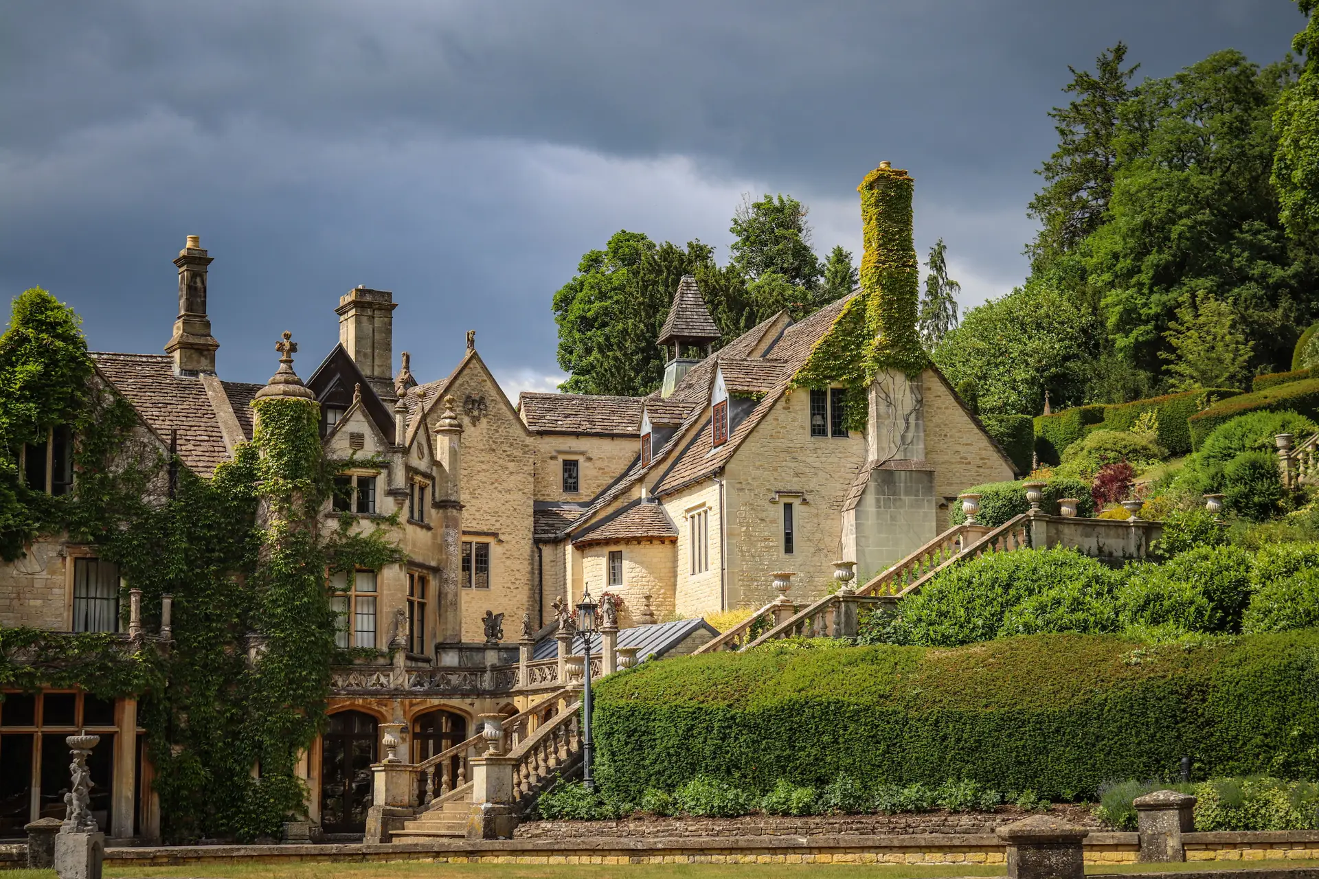 Scenic view of a historic manor house surrounded by lush green gardens in Castle Combe, England