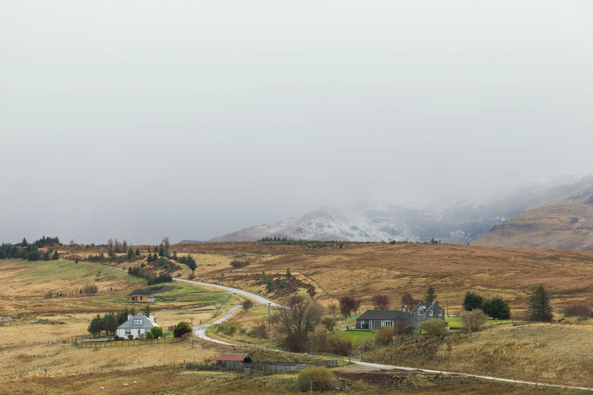 Tranquil Scottish countryside houses nestled under misty rolling mountain ranges