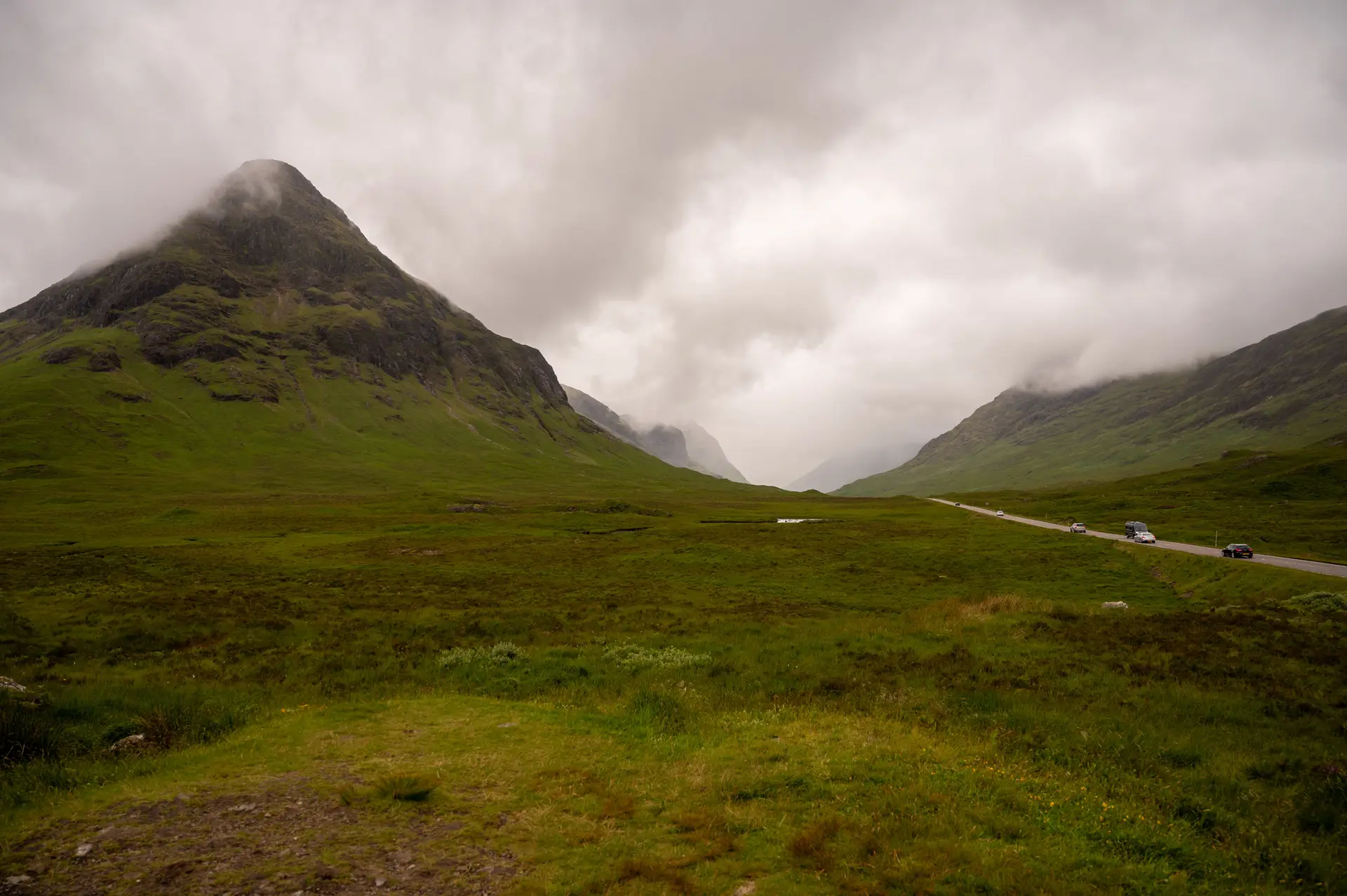 Misty winding road through lush Scottish highlands with green mountain slopes