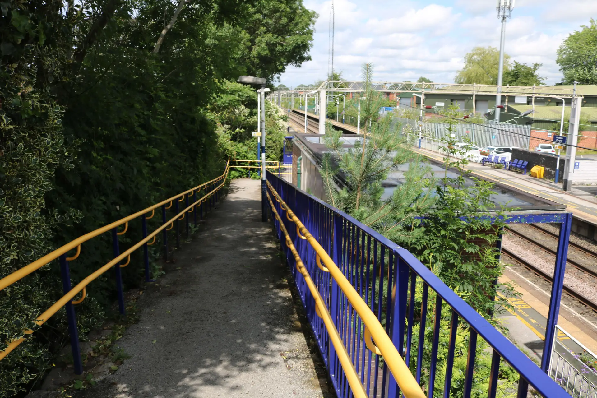 Scenic gentle paved access path leading to railway station platform in Cheshire